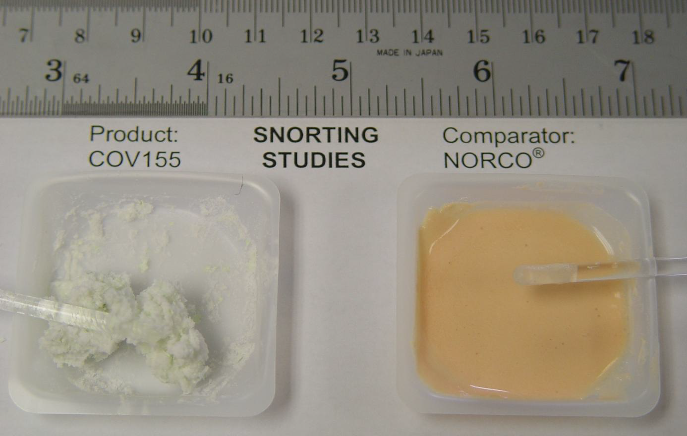 Two small plastic containers one labeled "Product: COV155" and the other labeled "Snorting Studies". On the left side of the image there is a small white container with a spoon in it. The container on the right side is filled with a yellow-colored liquid which appears to be a sample of Norco. The label on the container reads "Comparator: Norco". The background is white and there is also a ruler next to the containers.