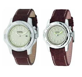 Two Fossil watches. The watches have a round silver-colored case with a beige dial. The dial has the Fossil logo in the center and the brand name "Fossil" written in black. The watch has a date window at the 3 o'clock position and a tachymeter scale on the bezel. The strap is made of brown leather with white stitching around the edges. Both watches appear to be new and unused.