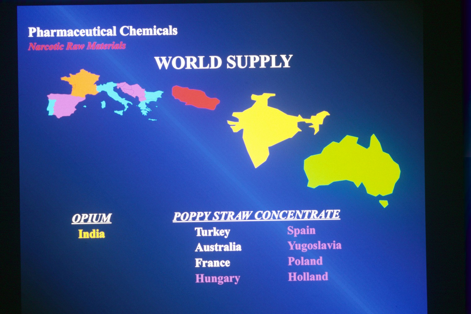 A map of the world supply of pharmaceutical chemicals. The map is divided into different countries with each country represented by a different color. The countries are labeled with their respective names such as India Turkey Austria France Hungary Spain and Poland. <br /><br />The map also shows the locations of poppy straw concentrate in each country. The colors of the countries are blue green yellow and pink representing the different countries. The text on the map reads "Pharmaceutical Chemicals" and "World Supply". The background of the image is dark blue making the colors of these countries stand out.