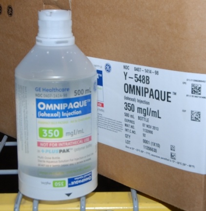 A white plastic bottle with a white cap and a label that reads "OMNIPAQUE" and "350 mg/ml". The label also has a barcode and a QR code on it. The bottle is placed on a yellow metal rack next to a cardboard box. The label on the bottle reads "GE Healthcare 500 ml" and the label also mentions that the bottle contains 350 mg/mL of the product. The box appears to be unopened and is sitting on a shelf.