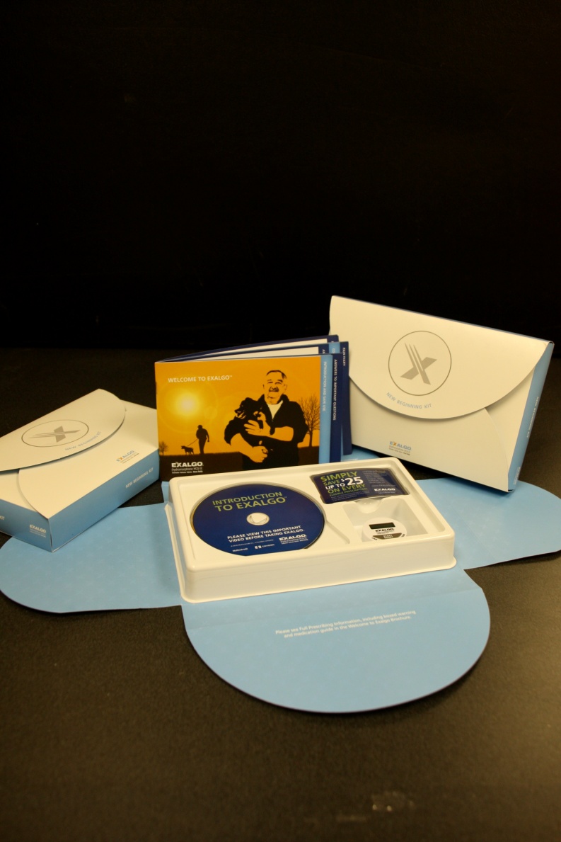 A collection of items arranged on a black surface. There are three items in the image - a white envelope a blue CD case and a white box with a blue cover. The CD case is open revealing the contents inside. The box has a picture of a man holding a guitar and the words "Welcome to the world" written on it. The other two items are also white and appear to be related to the CD case. The background is dark making the items stand out.