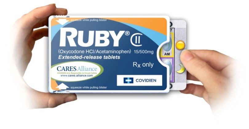 A hand holding a pack of Ruby II extended-release tablets. The pack is rectangular in shape and has a blue and orange label with the brand name "Ruby II" written in bold white letters at the top. Below that there is a description of the product which states that it is Oxycodone HCI/Acetaminophen 15/500mg Extended-release Tablets. The label also mentions that the tablets are available for purchase at CARESAlliance and Covidien. On the right side of the pack there are two tabs one labeled "Rx only" and the other labeled "Covidien". The background of the image is white.