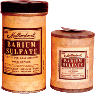 Two tins of Barium Sulfate. The tins are cylindrical in shape with a black lid on top. The label on the tins is orange and white with black text. The text on the label reads "Barium sulfate" in large bold letters. Below the text there is a smaller text that reads "Sulfate for L-ray diagnostics" in smaller black letters. <br /><br />The tins appear to be old and worn with some discoloration and scratches on the surface. The lid is slightly open revealing the contents inside. The background of the image is white.