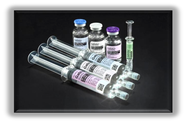 A set of six syringes arranged in a row on a black background. There are six vials of different sizes and colors - one with a blue cap another with a purple cap and the third with a green cap. Each vial has a label on it with a barcode and some text. The vials appear to be filled with a clear liquid possibly a vaccine or a similar substance. There is also a small syringe on the right side of the image. The image appears to be taken from a top-down perspective looking down on the vials.