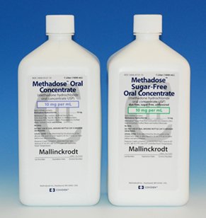 Two white plastic bottles of Methadose Oral Concentrate. The bottles are identical in size and shape with a white cap on top. The label on the bottles is blue and white with the brand name "Malthadose" and the product name "Sugar-Free Oral Concentrates" written in bold black letters. The bottle on the left is labeled "10 mg per ml" and has a label that reads "Mallinckrodt". The label also has a small illustration of a toothbrush and a toothpaste tube. The background of the image is a light blue color.