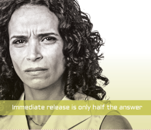 A black and white portrait of a woman with curly hair. She appears to be in her late 40s or early 50s and has a serious expression on her face. The background is plain white and there is a text overlay on the image that reads "Immediate release is only half the answer."