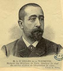 A black and white portrait of M. le Dr. Gilles de la Tourette. He is shown from the waist up facing the viewer with a serious expression on his face. He has a full beard and mustache and his hair is neatly combed back. The man is wearing a suit and tie and there is a label on the right side of the image that reads "Medecin des Hippieaux de Paris directeur en chef du service medical de l'Exposition de 1900." The label also has a logo of the E.M.P.P. which is a French government agency.