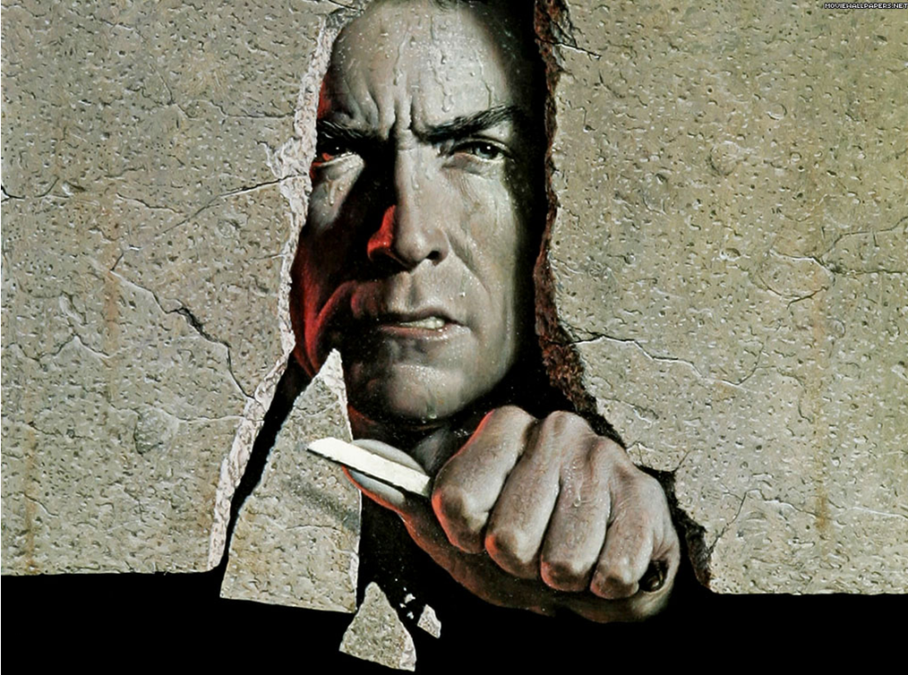 A digital art piece that appears to be a portrait of a man's face peeking through a crack in a concrete wall. The man is holding a knife in his right hand and is pointing it towards the viewer with his left hand. His face is contorted in a fierce expression with his eyes narrowed and his mouth slightly open. The background is a light beige color and the cracks on the wall are jagged and uneven. The overall mood of the image is intense and dramatic.