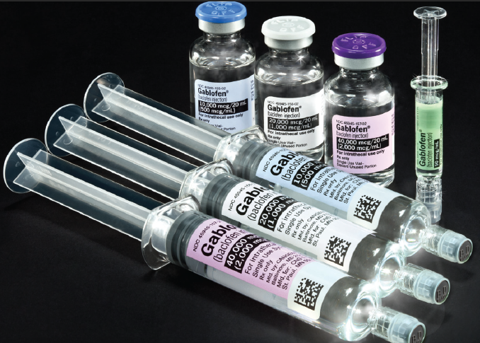 A group of four syringes and three bottles of Gablofen of different sizes and shapes arranged in a row on a black background. All the vials appear to be made of clear plastic (or glass?) and have a cylindrical shape.