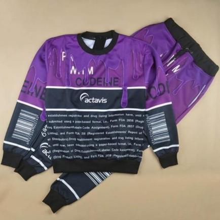 A purple sweatshirt and pants set with a black and white design. The sweatshirt has a round neckline and long sleeves while the pants have an elastic waistband and cuffed ankles. The design on the sweatshirt is a combination of purple and black with the word "cuddling" written in bold white letters at the top. Below the word there is a arcade and the brand name "activist" in smaller white letters. The set appears to be made of a soft comfortable fabric and is laid flat on a beige background.
