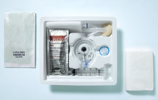 A medical kit in a white plastic container. The container is open and contains various medical supplies. On the left side of the container there is a white bandage with the words "Latex-Free Medium Glove" printed on it. Next to it there are two small white bandages one with a blue label and the other with a white label. <br /><br />In the center of the image there appears to be a syringe with a needle and a needle holder. The syringe is filled with a clear liquid and there are several other medical supplies scattered around it. The background is a light blue color.