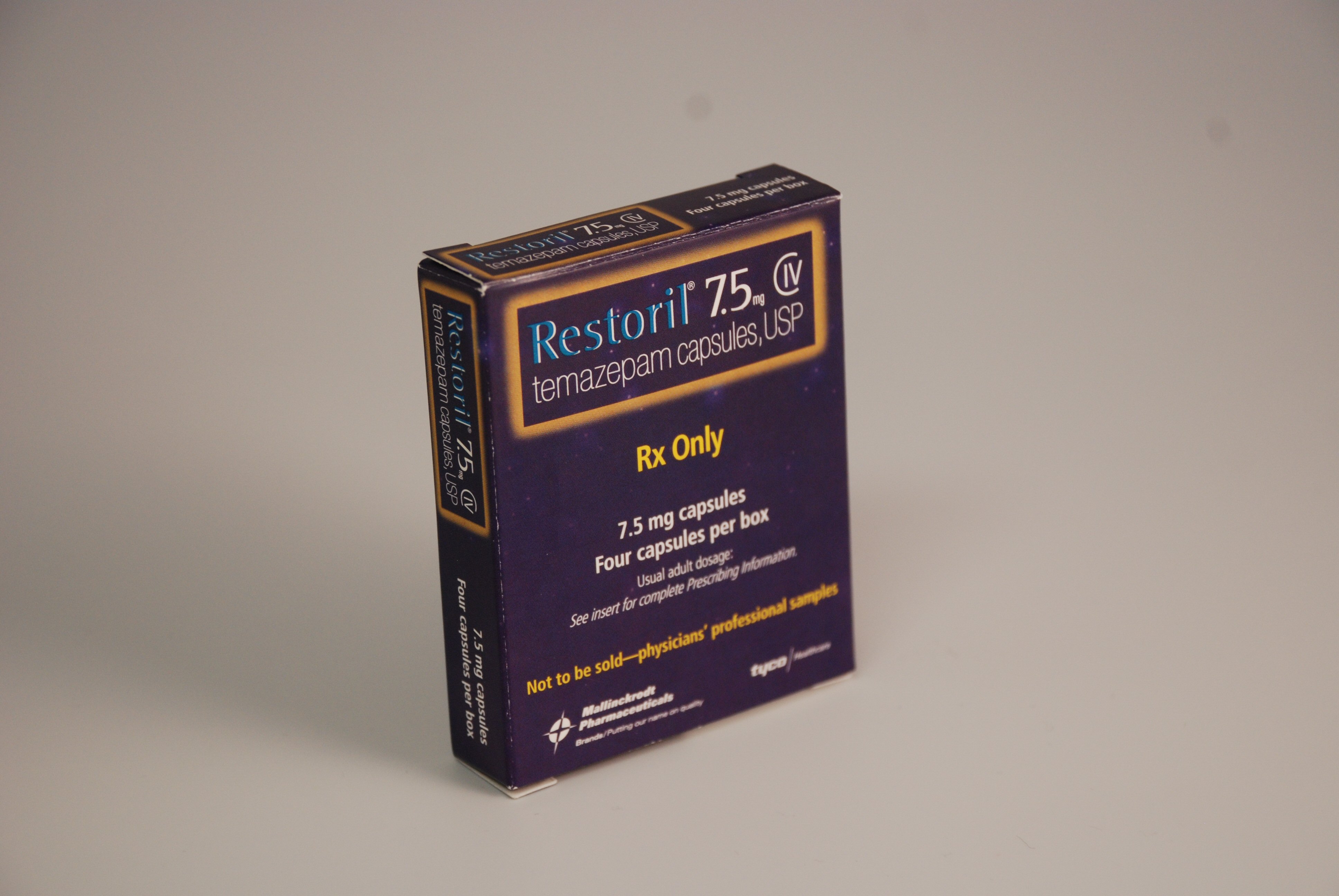 A photograph of a purple-colored rectangular box of Restoril 7.5 mg temazepam capsules USP. The label has the brand name "Restoril" written in bold blue letters at the top followed by the product name "7.5mg tablets" in smaller white letters. Below that it states that it contains 4 capsules per box. The background of the image is grey.