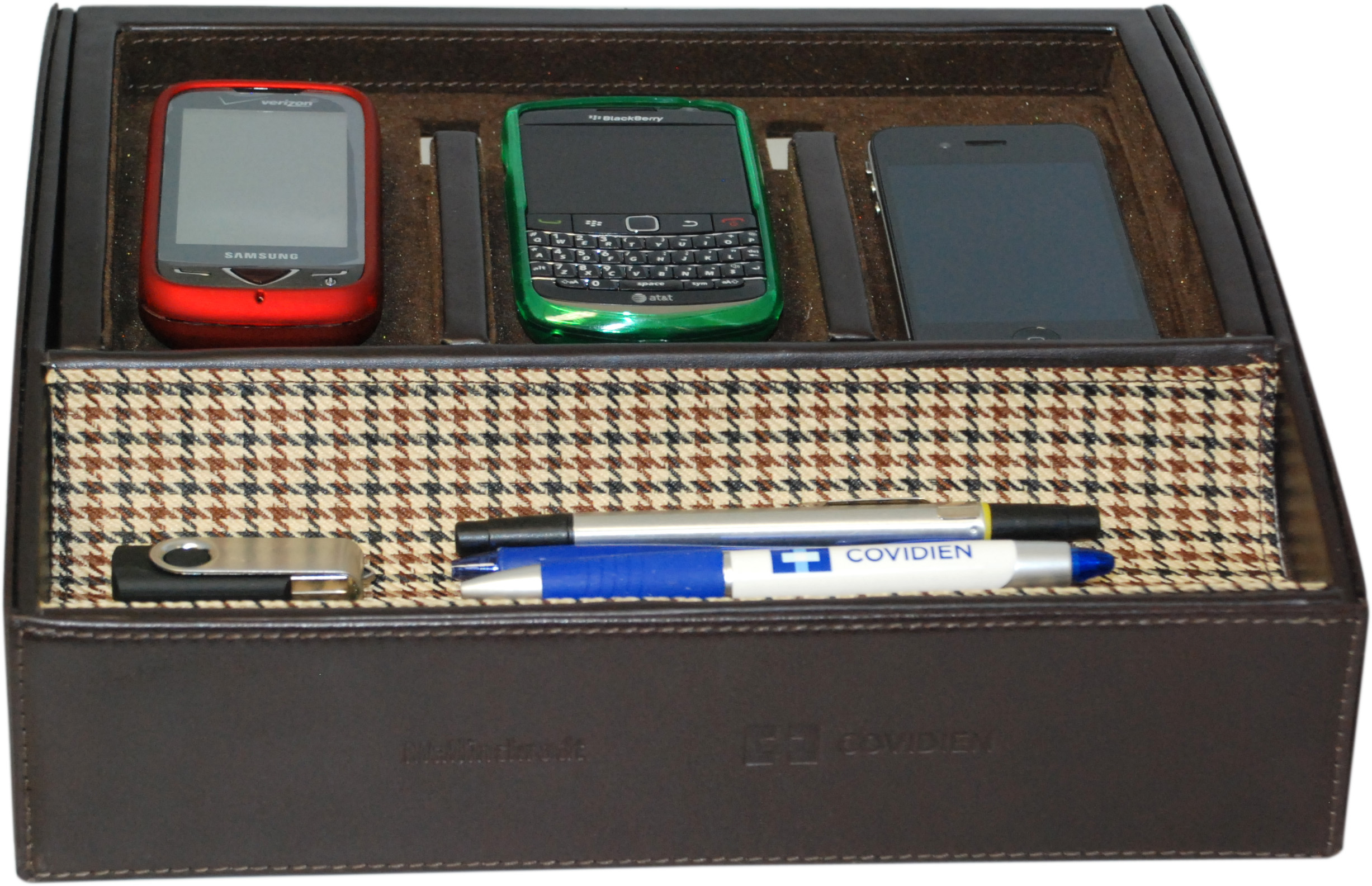 A brown leather box with a houndstooth pattern. Inside the box there are three mobile phones - a red Samsung phone a green BlackBerry phone and a black smartphone. There is also a blue and white pen with the word "COVIDINE" written on it. The box appears to be open revealing the contents inside.