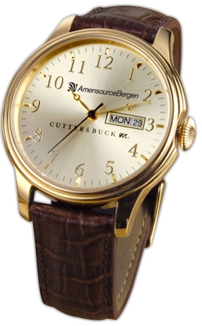 Of a wristwatch. The brand is Cutler & Buck and it is branded with the word "AmersourceBergen" on the face of the watch. The watch has a round gold-colored case. The time is 10:10 and there is a date window at the 3 o'clock position showing that it is Monday the 29th.<br /><br />The watch is attached to a brown leather strap with a buckle closure. The strap has a crocodile-embossed pattern on the sides. The overall design of the watch is elegant and sophisticated.