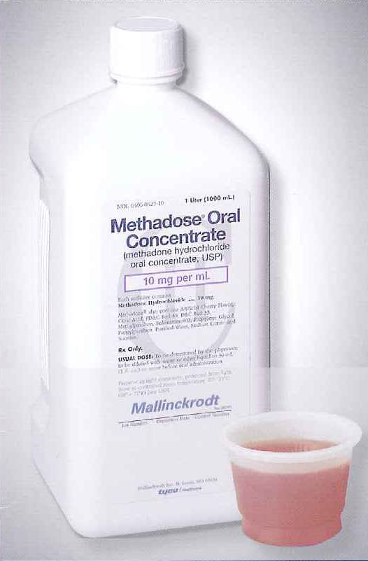 A white plastic bottle with a white cap and a small plastic cup next to it. The bottle is labeled "Methadose Oral Concentrate" and has a label that reads "10 mg per ml". The cup appears to be filled with a pinkish-red liquid. The background is plain white.