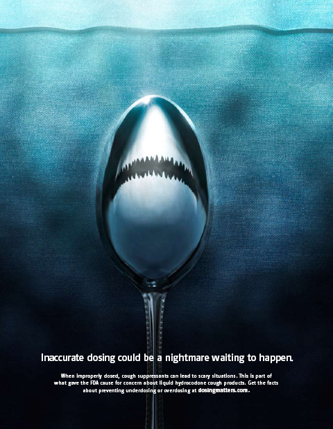 A digital art piece that features a spoon with a shark's mouth on it. The spoon is in the center of the image with the mouth open wide revealing sharp teeth. The background is a dark blue color and the spoon is positioned in the middle of the frame. The text on the image reads "Inaccurate dosing could be a nightmare waiting to happen." Smaller text underneath reads "When improperly dosed cough suppressants can lead to scary situations. This is part of what gave the FDA cause for concern about liquid hydrocodone cough products. Get the facts about underdosing or overdosing at dosingmatters.com." The text is written in white and is in a modern sans-serif font. The overall tone of the piece is dark and ominous conveying a sense of fear and uncertainty.