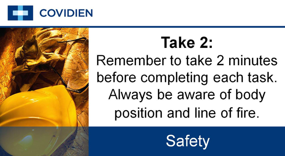 A slide from a presentation by COVIDIEN about safety. It has a blue background with white text. On the left side of the slide there is an image of a yellow hard hat lying on the ground. The text on the slide reads "Take 2: Remember to take 2 minutes before completing each task. Always be aware of body position and line of fire." Below the text there are two bullet points that read "Safety" and "COVIDIEN".