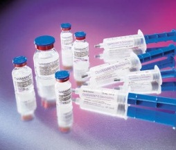 A group of small vials with blue caps and white labels. The vials are arranged in a scattered manner on a purple background. There are six vials in total with the largest one in the center and the smallest one on the right side. Each vial has a blue handle and a white label with black text. The labels appear to be for a medical or pharmaceutical product. The background is blurred making the vials the focal point of the image.