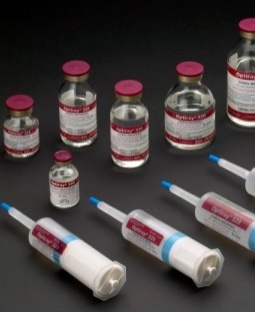 A group of six small glass vials with red caps and white labels. The vials are arranged in a scattered manner on a black background. There are six of the vials in total with the largest one in the center and three smaller ones on either side. Each vial has a blue cap and a white label with red text. The labels appear to be for a medical or pharmaceutical product as indicated by the text on the labels. There is also a syringe with a blue handle on the right side of the image.