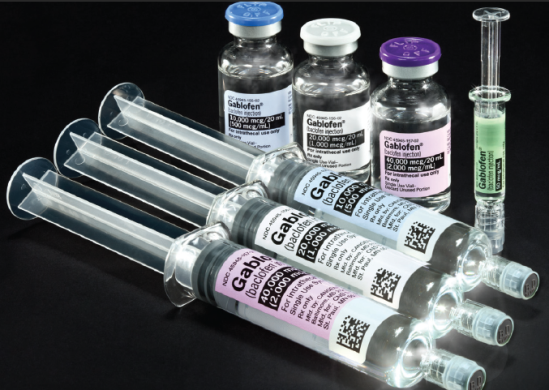 A group of six syringes of different sizes and shapes arranged in a row on a black background. There are six vials of different colors - one with a blue cap another with a purple cap the third with a white cap and the fourth with a green cap. All the vials have labels on them with the word "Gabor" written on them. The vials appear to be filled with a clear liquid possibly a vaccine or a similar substance. There is also a small syringe with a needle on the right side of the image.