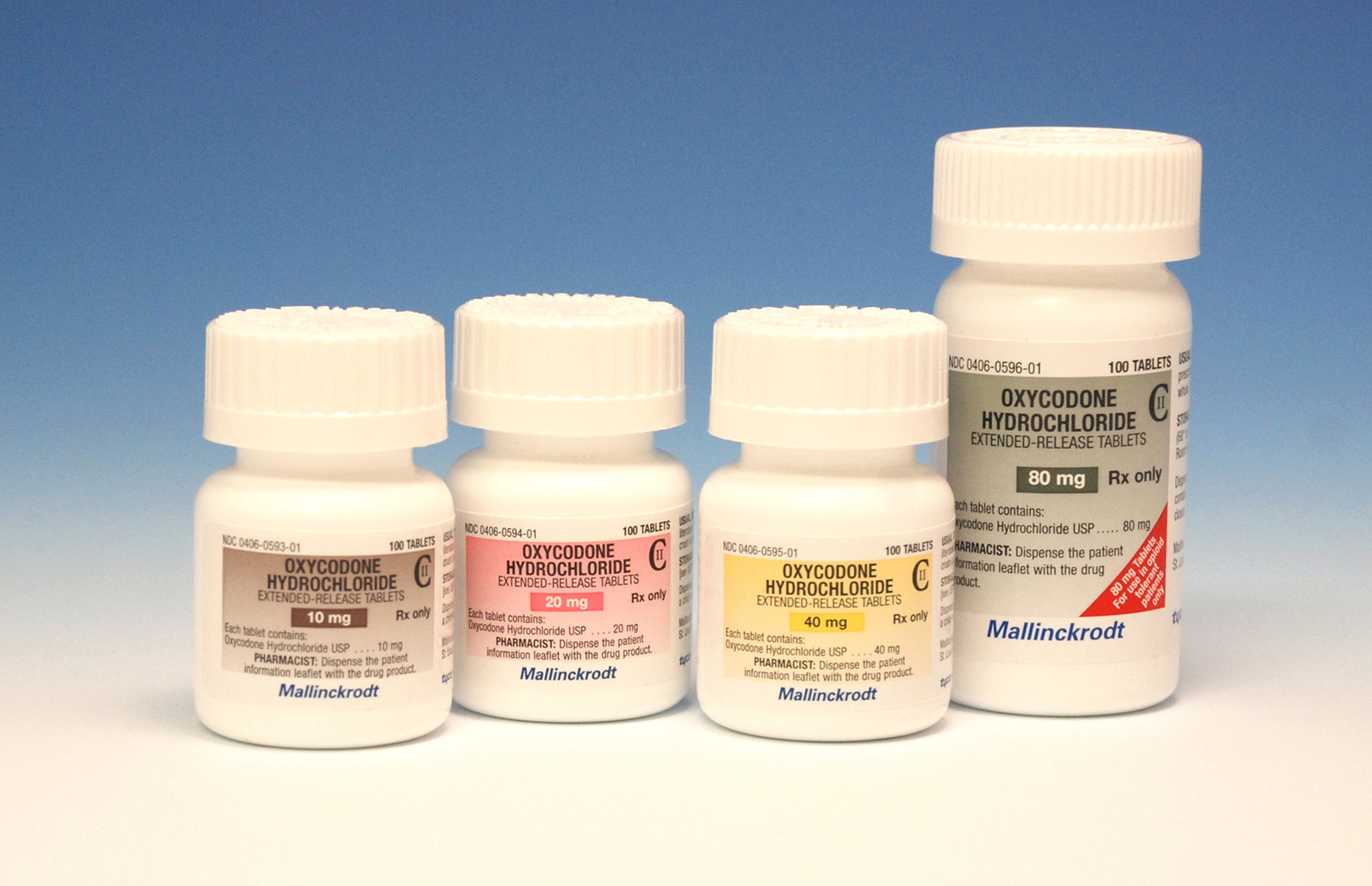 Four white medicine bottles with white caps. The bottles are arranged in a row with the first bottle on the left the second bottle in the middle and the third bottle at the bottom. All the bottles have the brand name "Oxycodone Hydrochloride" written on them in red and yellow letters. The label also mentions that the bottles contain 80mg of the medication. The background is a solid blue color.