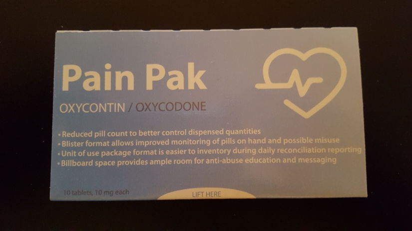 A photograph of a box of Pain Pak Oxycontin/Oxycodone tablets. The box is rectangular in shape and has a light blue background. On the front of the box there is a white label with black text that reads "Pain Pak" in large bold font. Below the text there are two lines of text that read "Reduced pill count to better control dispensed quantities" and "Blister format allows improved monitoring of pills on hand and possible misuse". <br /><br />On the right side of the label it says "Unit of use package format is easier to inventory during daily reconciliation reporting. Billboard space provides ample room for anti-abuse education and messaging. 10 tablets 10 mg each. Lift here." There is also a small illustration of a heart with a heartbeat line on the top right corner.