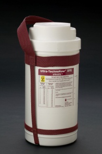 A white cylindrical container with a red strap attached to it. The container appears to be made of plastic and has a label on it that reads "Ultra-Technikkeur DTE". The label also has some information about the product such as its size capacity and other specifications. The strap is secured around the container with two red straps. The background is black making the container stand out.