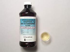 A black plastic bottle with a white cap. The label on the bottle reads "Hydrocodone Bitartrate and Acetaminophen Elixir". The label also mentions that the product is 16 fl oz (473 ml) in size. The bottle is placed on a white surface and there is a small white cap next to it.