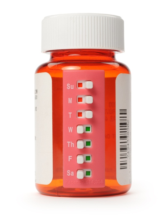 Of an orange-colored medicine bottle with a white cap. The bottle is rectangular in shape and has a label on the front with the letters "Su" "M" "T" "W" "Th" "F" "G" "H" "J" "K" "L" and "E" written on it. The label also has a barcode on the right side. The background is white and the bottle appears to be empty.