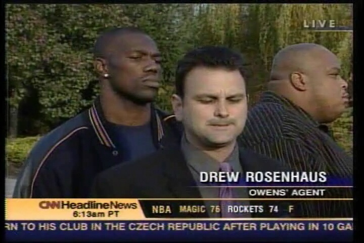 A screenshot from a CNN Headline News segment. It shows three men standing in a row with the man in the middle wearing a suit and tie. The man on the left is wearing a black jacket and appears to be in his late twenties or early thirties. He has short dark hair and is looking off to the side with a serious expression on his face. On the right side of the image there is another man wearing a striped shirt and is also looking off into the distance. The man in the center appears to be speaking and he is identified as "Drew Rosenhaus Owens' Agent".