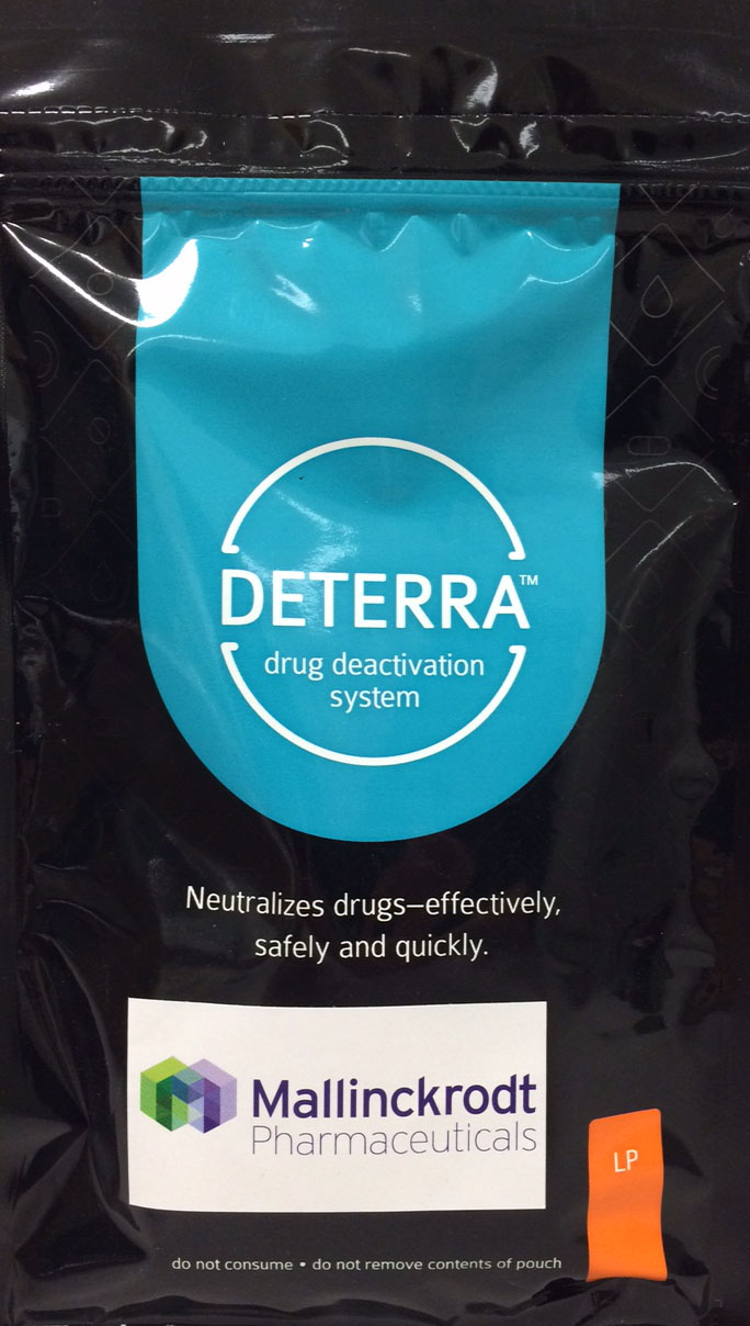 Of a black plastic pouch with a blue label on it. The label has the brand name "DETERRA" written in white letters at the top followed by the logo of the drug deactivation system. Below the logo there is a text that reads "Neutralizes drugs-effectively safely and quickly." The label also mentions that the product is from Mallinckrodt Pharmaceuticals a pharmaceutical company. The pouch has an orange label on the bottom right corner that says "Do not consume - do not remove contents of pouch".