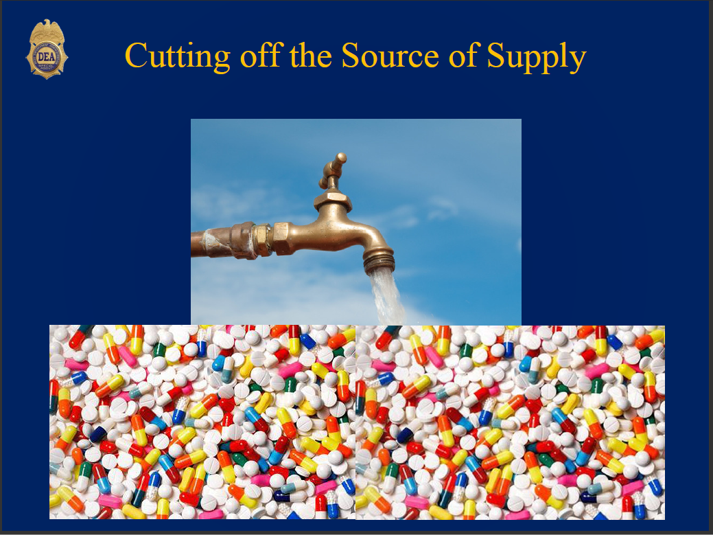 A faucet with water flowing out of it. The tap is made of brass and has a handle on one side. The water is flowing from the tap into the other side of the image. The background is a blue sky with white clouds. Below the tap there is a pile of colorful pills or capsules in various colors including red orange yellow green blue and purple. The pills are scattered across the image creating a mosaic-like effect. The image is accompanied by text that reads "Cutting off the Source of Supply".