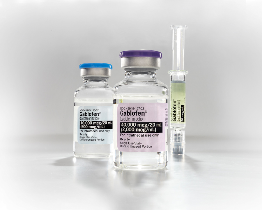 Three vials of different sizes and shapes. The vials are made of clear glass and have a purple lid. Each vial has a label on it that reads "Gablofen" in white letters. The label also mentions that the vials contain 40000 mg/ml of the product. Next to the vial there is a small syringe with a green liquid inside. The background is white and the vases are arranged in a triangular formation.