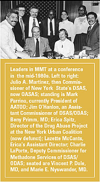 A black and white photograph of a group of people sitting around a table. The photograph appears to be from a conference or meeting as indicated by the text on the right side of the image. The people in the photograph are of different ages genders and ethnicities. They are all dressed in formal business attire.<br /><br />The photograph is taken from a high angle looking down at the table and smiling at the camera. The table is covered with a white tablecloth and there are several glasses and plates on it. The text on this image reads "Leaders in MMT at a conference in the mid-1980s. Left to right: Julio A. Martinez then Commissioner of New York State's DSAS now OASAS; standing is Mark Parrino currently President of AATOD; Jim O'Hanlon an Assistant Commissioner of DASAS/ODAS; Barry Primm MD; Erica Spitz Director of the Drug Abuse Project at the New York Urban Coalition (now defunct); Lazette McCants Erica's Assistant Director; Charlie LaPorte Deputy Commissioner for Methadone Services of DSAS/ODAS; seated are Vincent P. Dole MD and Marie E. Nyswander MD."