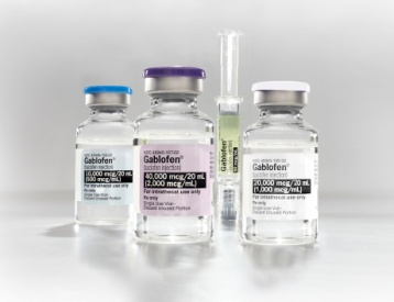 Three small glass vials with blue lids and white labels. The vials are arranged in a row with the first vial on the left the second vial in the middle and the third vial at the bottom. Each vial has a label with the name "Gablofen" written on it in black text. The label also mentions that the vials contain 20000 mg/ml of the medication. The first vials have a purple cap and the second one has a clear glass tube with a green liquid inside. The background is plain white.