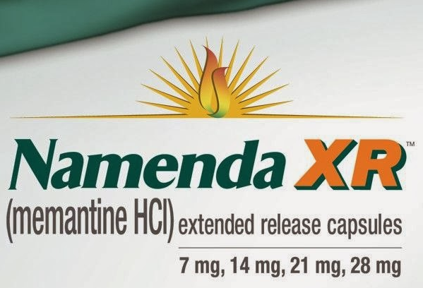 A label for Namenda XR (Mementine HCI) extended release capsules. The label is white with a green background and the Namenda logo in the center. The logo is a yellow sunburst with a red and orange flame in the middle. Below the logo there is text that reads "Namenda Xu" in bold black letters. The text below the logo reads "7 mg 14 mg 21 mg 28 mg". The label also mentions that the capsules contain 7 mg of the medication.