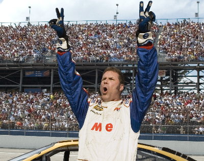 A man standing on top of a race car with his arms raised in the air. He is wearing a blue and white racing suit with the word "Me" written on it. The man appears to be celebrating with his mouth open and his eyes closed. In the background there is a large crowd of people in the stands and the sky is cloudy. The image appears to have been taken at a NASCAR race.