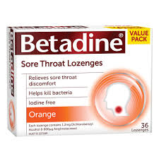 Of a box of Betadine Sore Throat Lozenges. The box is white with red and orange accents. The brand name "Betadine" is written in bold red letters at the top of the box. Below the brand name it says "Relieves sore throat discomfort" in smaller red letters. <br /><br />The box also mentions that the product helps kill bacteria iodine free and orange. There is also an image of a lightbulb on the right side of the label. The label also states that it contains 36 lozenges and is available in a value pack.