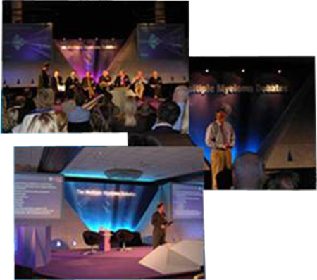 A collage of three photographs of a stage set up for a conference or event. The stage is decorated with blue and purple lights and there is a large screen at the front of the stage. On the left side of the image there are rows of people standing on the stage and on the right side there is an audience of people sitting in chairs. In the center of the collage a man is standing at a podium and speaking into a microphone. He is wearing a suit and tie and appears to be giving a speech or presentation. The background is dark and the stage is lit up with blue lights.