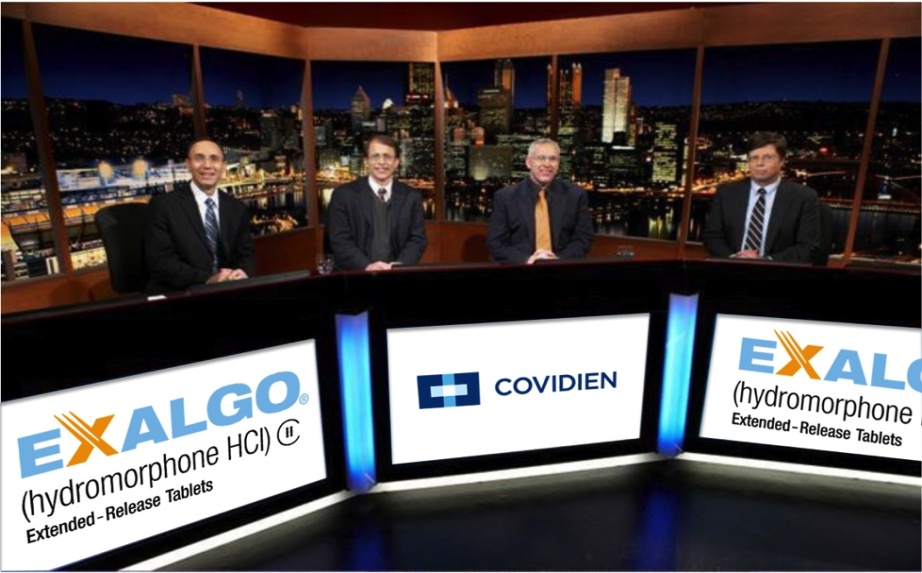 Four men sitting at a desk in front of a large window with a view of a city skyline at night. They are all wearing suits and appear to be in a news studio. On the desk there are three large screens displaying the logos of Exalgo Covidien and Hydromorphone HCI (Extended-Release Tablets). The men are smiling and looking at the camera. The background shows a cityscape with tall buildings and skyscrapers.