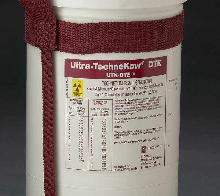 A white plastic container with a red strap attached to it. The label on the container reads "Ultra-Technekow® DTE UTK-DTE" in bold black letters. Below the label there is a list of specifications for the product including the product name size and other information. The container appears to be made of plastic and has a cylindrical shape. The background is dark making the label stand out.