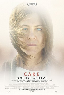 A movie poster for the film "Cake" starring Jennifer Aniston. The poster features a close-up of the actress's face with her blonde hair and blue eyes looking directly at the camera. She is wearing a white t-shirt and has a serious expression on her face. The background is blurred but it appears to be a cityscape with buildings and trees. The title of the film is written in bold red letters at the top of the poster with the tagline "In theaters everywhere this January" written in smaller red letters below.