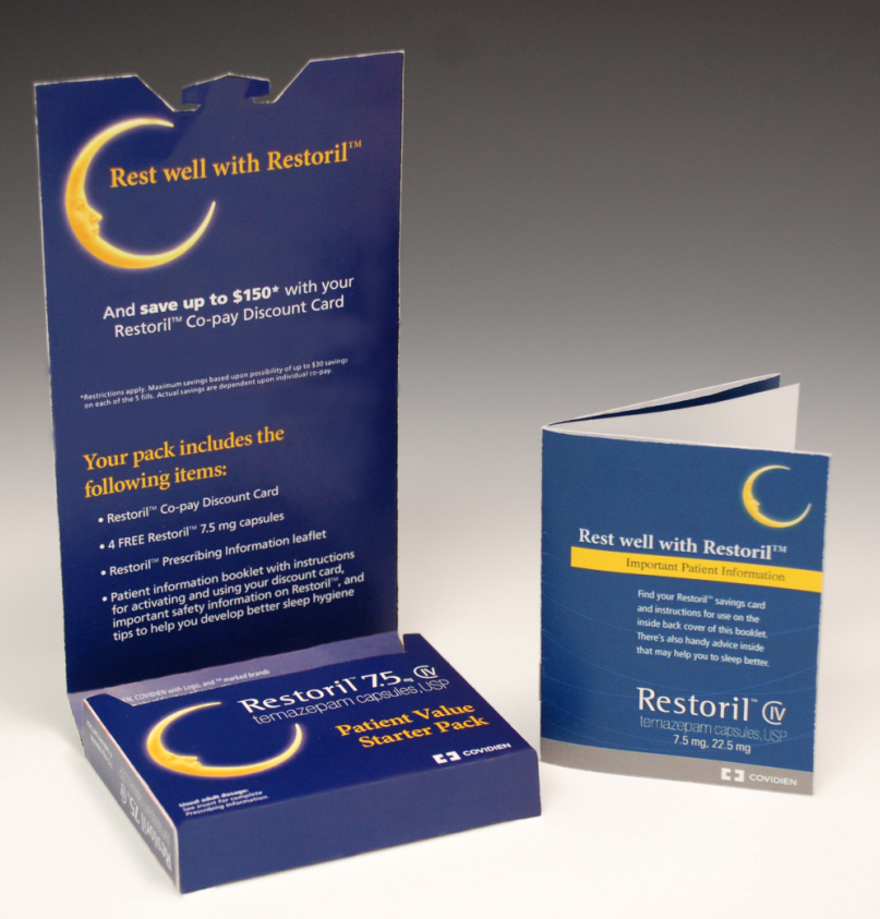 A blue cardboard box with the text "Rest well with Restoril" printed on it. The box is open revealing the contents inside. On the left side of the box there is a text that reads "And save up to $150 with your Restoril Co-Pay Discount Card". On the right side there are two smaller boxes one with the same text and the other with a yellow crescent moon design. The boxes appear to be new and unused. The background is white.