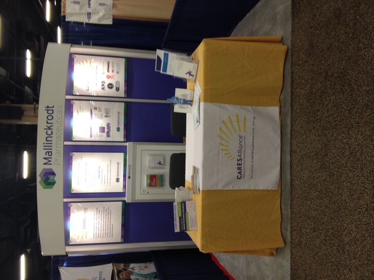 A booth at a trade show or exhibition. The booth has a blue background with a white banner on the left side that reads "Mallorca" in bold letters. On the right side of the booth there is a yellow tablecloth with a logo of a sun on it. In front of the tablecloth there are several white boxes with information about the booth. The boxes are arranged in a grid-like pattern and appear to be part of a larger display. There are also several pamphlets and brochures on the table. The floor is carpeted and there are other booths visible in the background.