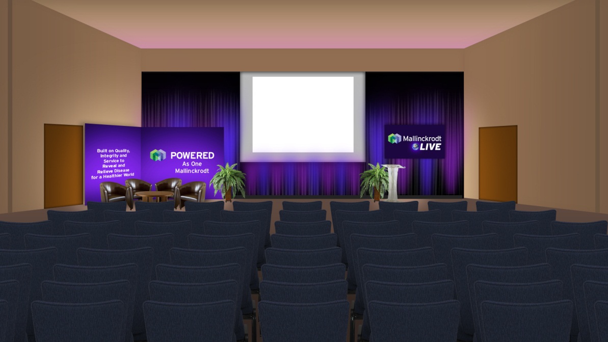 A large conference room with rows of blue chairs facing a stage. The stage is set up with a purple curtain and a large screen at the front. On either side of the stage there are two purple banners with the words "Powered" and "Live" written on them. There are also two potted plants on the stage and a podium in front of the screen. The room has a high ceiling with recessed lighting. The overall atmosphere of the room is professional and modern.