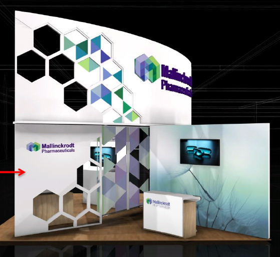 A trade show booth with a modern design. The booth has a white background with a geometric pattern of hexagons in different colors. On the left side of the booth there is a large banner with the company's logo and name in purple and green. Next to the banner there are two smaller banners with the same logo and the company name in blue and green colors. <br /><br />The booth also has a small desk in front of it with a computer monitor on it. The desk has a red arrow pointing to the right side indicating that the booth is for a company called Mallinckrodt Pharmaceuticals. The overall design is sleek and professional with a focus on the company and its products.