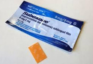 A blue and white packet of Suboxone 8mg/2mg sublingual film. The packet is rectangular in shape and has the brand name "Suboxone" written in bold white letters on the top left corner. Below that there is a description of the product written in smaller white letters. On the right side of the packet there are two orange-colored strips of the film one of which is slightly larger than the other. The strips appear to be made of plastic and are lying on a white surface.