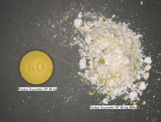 A yellow pill with the number 40 on it lying on a black surface. The pill is labeled "Purdue Oxycontin OP 40 mg". Next to the pill there is a pile of white powder with yellow flecks in it. The powder is labeled "Purdue Oxycontin OP 40 mg Milled".