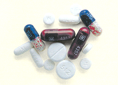 A group of pills scattered on a beige background. There are several pills of different sizes and colors including blue red pink and white. Some of the pills have the letters "M" and "A357" written on them while others are plain white. The pills appear to be of different shapes and sizes with some being round and others being oval-shaped.