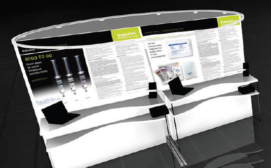 A 3D rendering of a trade show booth. The booth is white with a curved design and has a black and yellow banner at the top. The banner has the words "Good to go" written in bold black letters. Below the banner there is an image of three syringes with different sizes and colors. On the right side of the booth there are two black stands with a computer monitor and other information displayed on them. The background is black making the booth stand out.